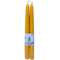 A pair of pure British beeswax taper candles standing elegantly in brass holders on a dining table.