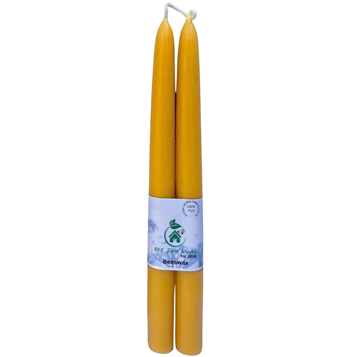 A pair of pure British beeswax taper candles standing elegantly in brass holders on a dining table.